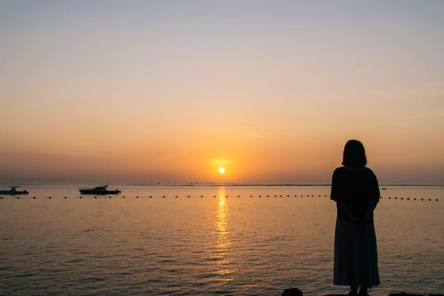 夕焼けの海を見る女性